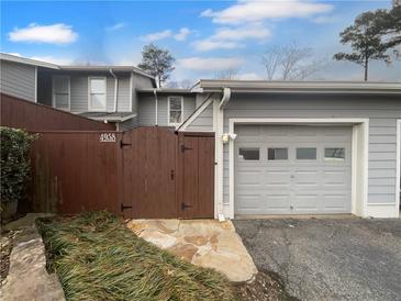 Charming townhome featuring a one-car garage and inviting wooden privacy fence and entrance at 4958 Meadow Ln, Marietta, GA 30068