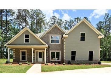 Charming two-story home with brick and siding, complemented by a well-manicured lawn and lush greenery at 121 Honey Creek Rd, Conyers, GA 30094