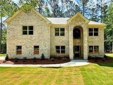 Charming, light brick two-story home featuring a manicured lawn and a welcoming, arched entryway at 123 Honey Creek Rd, Conyers, GA 30094