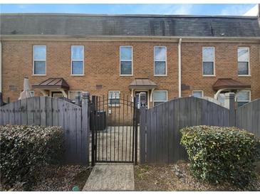 Brick townhome with a gated entrance and manicured bushes around the property at 165 N River Dr # G, Atlanta, GA 30350