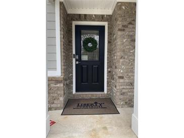 Charming front entry features a black door, brick surround, and a welcoming wreath at 750 Great Oak Pl, Villa Rica, GA 30180