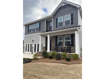 Charming two-story home featuring a welcoming front porch with rocking chairs and manicured landscaping at 750 Great Oak Pl, Villa Rica, GA 30180