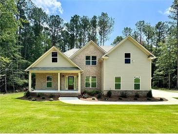 Charming two-story home with brick and siding exterior, lush green lawn, and mature trees at 125 Honey Creek Rd, Conyers, GA 30094