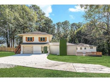 Two-story home with a one-car garage, quaint landscaping, a long driveway, and an expansive lawn at 3085 Remington St, East Point, GA 30344