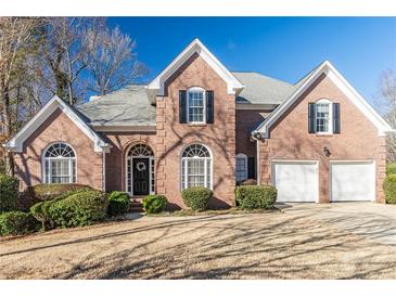 Stunning brick home featuring manicured landscaping, two-car garage, and a welcoming entrance at 7145 Hartsfield Pl, Suwanee, GA 30024