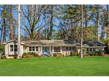 Charming brick ranch-style home boasts a lush lawn and mature trees at 1716 N Springs Dr, Atlanta, GA 30338