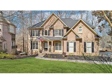 Beautiful two-story home featuring a manicured lawn, stone accents, and covered front porch with the American flag at 2883 Misty Rock Cv, Dacula, GA 30019