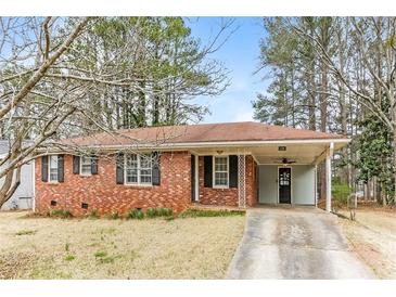 Cozy brick home featuring a covered carport and a well-maintained front yard surrounded by mature trees at 3588 Swallow Ln, Decatur, GA 30032