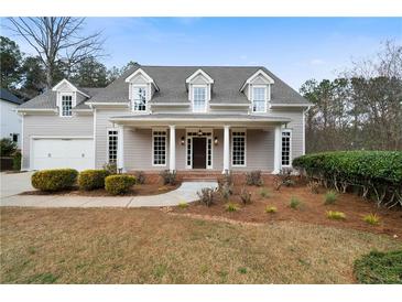 Charming two-story home with a covered front porch, dormer windows, and a well-maintained landscaped yard at 111 Carter Ln, Canton, GA 30115