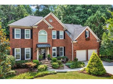 Charming two-story brick home featuring a well-manicured lawn, mature trees, and a two car garage at 2138 Jockey Hollow Nw Dr, Kennesaw, GA 30152