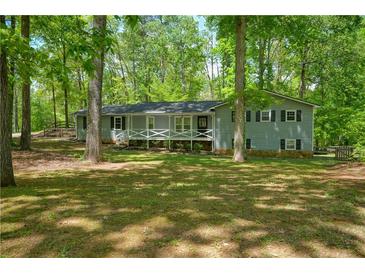 Charming single-story home with a cozy front porch, surrounded by mature trees and lush landscaping at 411 Buckingham Cir, Marietta, GA 30066