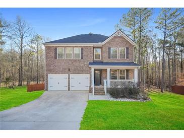 Charming two-story brick home featuring a two-car garage, covered porch, and manicured lawn at 13699 Inman Rd, Hampton, GA 30228