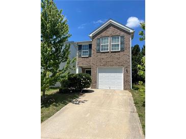 Two-story brick home featuring a two-car garage and well-maintained lawn with mature trees at 2056 Belmont Cir, Conyers, GA 30012