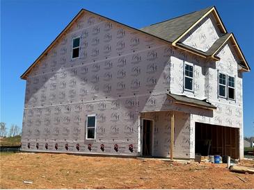 New construction home showing exterior framing details and wrapped for weather protection on a sunny day at 1227 Riverstone Rd, Jonesboro, GA 30238