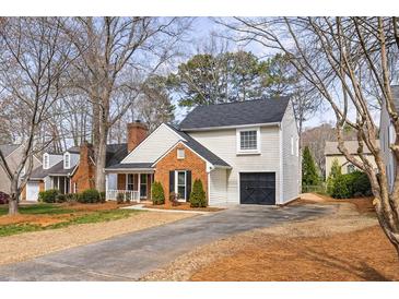 Charming home with a brick accent, well-manicured landscaping, and a long driveway leading to a one-car garage at 302 Roswell Green Ln, Roswell, GA 30075