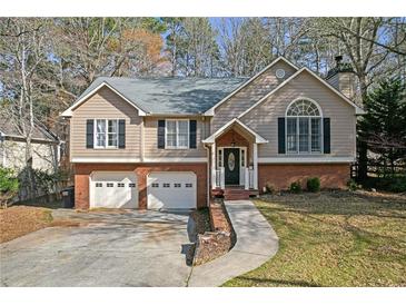 Charming two-story home with a two-car garage and a well-manicured lawn at 4142 Huntcliff Dr, Woodstock, GA 30189