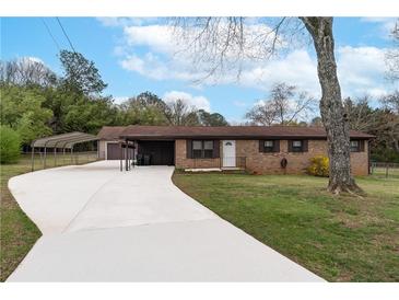 Charming brick home featuring a long driveway with covered parking at 3811 Lavilla Dr, Powder Springs, GA 30127