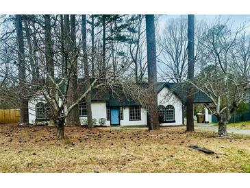 Charming one-story home with blue door and mature trees creating a private yard at 309 Peachtree Dr, Riverdale, GA 30274