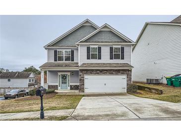 Charming two-story home featuring gray siding, stone accents, and a well-manicured front yard at 636 Georgia Way, Woodstock, GA 30188