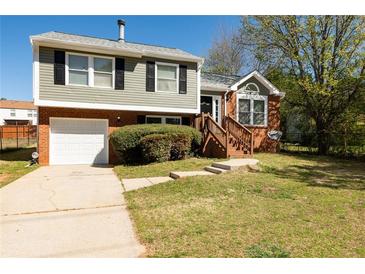 Charming two-story home featuring a brick facade, attached garage, landscaped yard, and inviting stairway to the front door at 6136 Marbut Rd, Lithonia, GA 30058