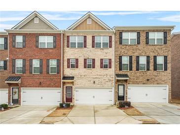 Charming townhomes featuring a brick facade, symmetrical windows, and attached garages for convenient parking at 3030 Westpoint Cir, Snellville, GA 30078