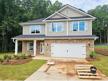 Two-story home featuring a brick and vinyl facade, a two-car garage, and well landscaped front yard at 305 Melanie Ct, Bowdon, GA 30108