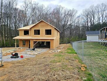 New construction home showcasing the initial framing stage with a large two-car garage nestled in a wooded lot at 305 Melanie Ct, Bowdon, GA 30108