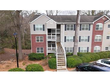 Exterior view of brick and vinyl apartment building with stairs and mature landscaping at 330 Teal Ct, Roswell, GA 30076