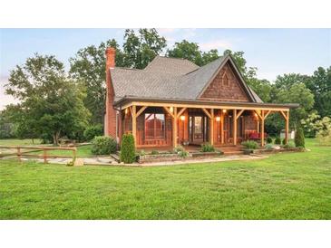 Charming home featuring a covered porch with timber beams, shingle siding, and mature landscaping at 1694 Mount Bethel Rd, Mcdonough, GA 30252