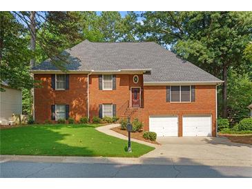 Charming brick home with a well-manicured lawn and a two-car garage nestled among lush trees at 4956 Braeburn Nw Trce, Acworth, GA 30102