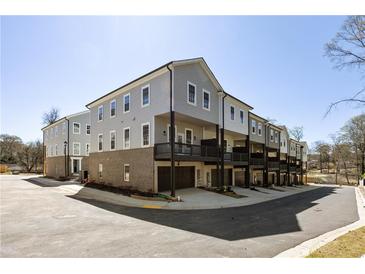 New townhome exterior featuring private garages, dark trim, light gray siding, and ample parking at 3165 Dogwood Dr # 107, Hapeville, GA 30354