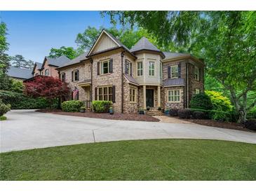 Stately stone home with manicured lawn, mature trees, and circular driveway at 2260 Wood Falls Dr, Cumming, GA 30041