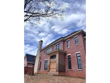 Two-story brick home featuring black-framed windows, chimney, and porch area awaiting finishing touches at 4881 Powers Ferry Nw Rd, Atlanta, GA 30327