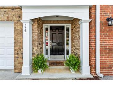Charming brick home entrance features a black door with white trim and decorative plants at 3736 Chattahoochee Summit Se Dr # 20, Atlanta, GA 30339