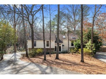 Charming home nestled among the trees with a stone accent and long driveway at 8498 Colony Club Dr, Alpharetta, GA 30022