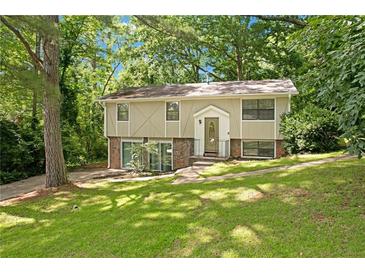 Split level home with lush green yard and a traditional front entrance surrounded by mature trees at 4690 Big Valley Ct, Stone Mountain, GA 30083