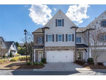 Charming townhome with stone accents, a two-car garage, and a beautifully landscaped front yard at 557 Stone Field Nw Run, Marietta, GA 30060