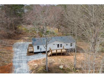 Quaint single-story home featuring a wooden deck and gravel driveway surrounded by trees at 75 Woodfield Rd, Covington, GA 30014