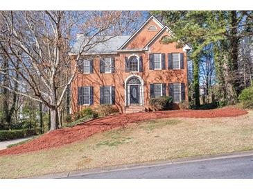 Charming brick two-story home featuring a well-manicured lawn and a classic front door with sidelights at 2542 Ashridge Ct, Lawrenceville, GA 30043