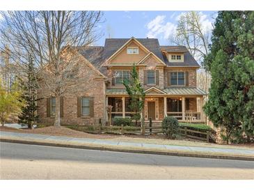 Inviting brick home featuring a covered porch, manicured landscaping, and charming architectural details at 2315 Monet Dr, Cumming, GA 30041
