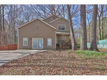 Two-story home featuring a front yard with mature trees and a well-maintained lawn on a sunny day at 585 Lake Dr, Snellville, GA 30039