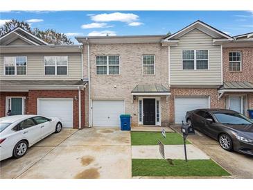 Townhome with a black front door, attached garage, and a well-manicured lawn at 5027 Lower Elm St, Atlanta, GA 30349