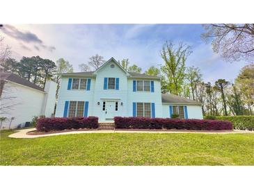 Charming two-story home featuring blue shutters, a well-maintained lawn, and beautiful landscaping at 4083 Rivermeade Sw Dr, Lilburn, GA 30047
