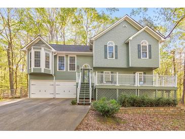 Charming exterior of home featuring a two-car garage and a spacious front porch with white railings at 1013 Harbor Ct, Woodstock, GA 30189
