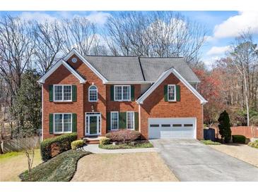 Charming two-story brick home featuring a two-car garage, well-manicured lawn, and traditional architectural details at 1168 Blackhawk Pl, Lawrenceville, GA 30043