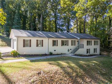 Charming single-story home with brick facade, dark shutters, and mature trees, offering a tranquil setting at 2418 Bolling Brook Sw Dr, Atlanta, GA 30311