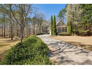 Charming traditional home with a long driveway lined with lush greenery and mature trees at 1345 Bridgemill Ave, Canton, GA 30114