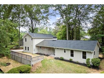Charming home with neutral siding, dark roof, and a partially fenced front yard, surrounded by mature trees at 6405 Cherry Tree Ln, Atlanta, GA 30328