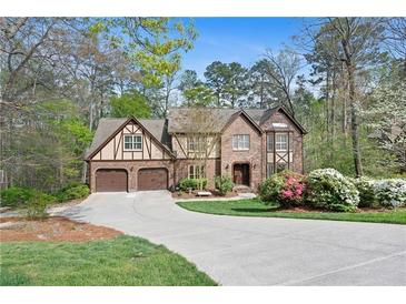 Charming brick home boasts a two-car garage, lush landscaping, and a welcoming driveway at 2702 Long Lake Ne Ter, Roswell, GA 30075