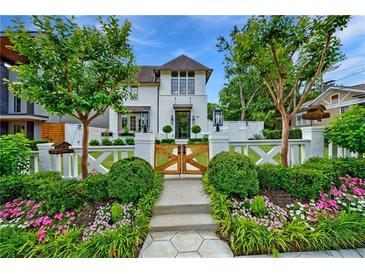 Charming white home featuring a landscaped front yard, wooden gate, and manicured bushes at 405 9Th Ne St, Atlanta, GA 30309